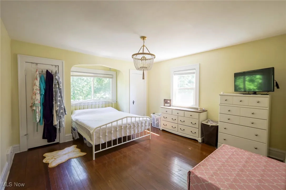 Bedroom featuring multiple windows, wood-type flooring, and a chandelier