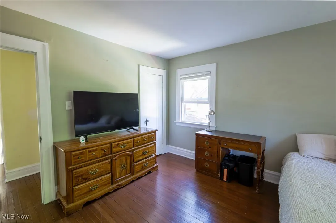 Bedroom with dark wood finished floors and baseboards