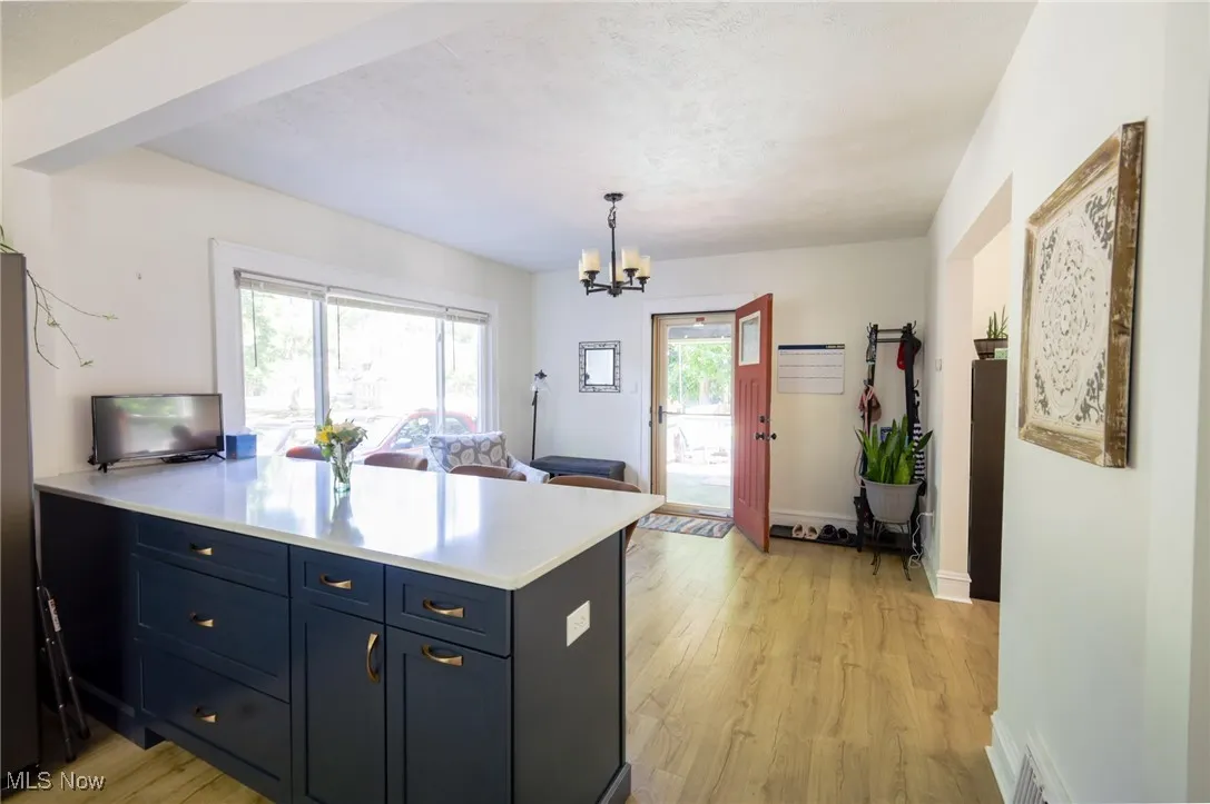 Kitchen featuring light wood-type flooring, a peninsula, light countertops, a chandelier, and pendant lighting