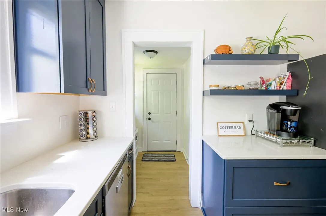 Kitchen featuring light wood-style floors, blue cabinets, dishwasher, and light countertops