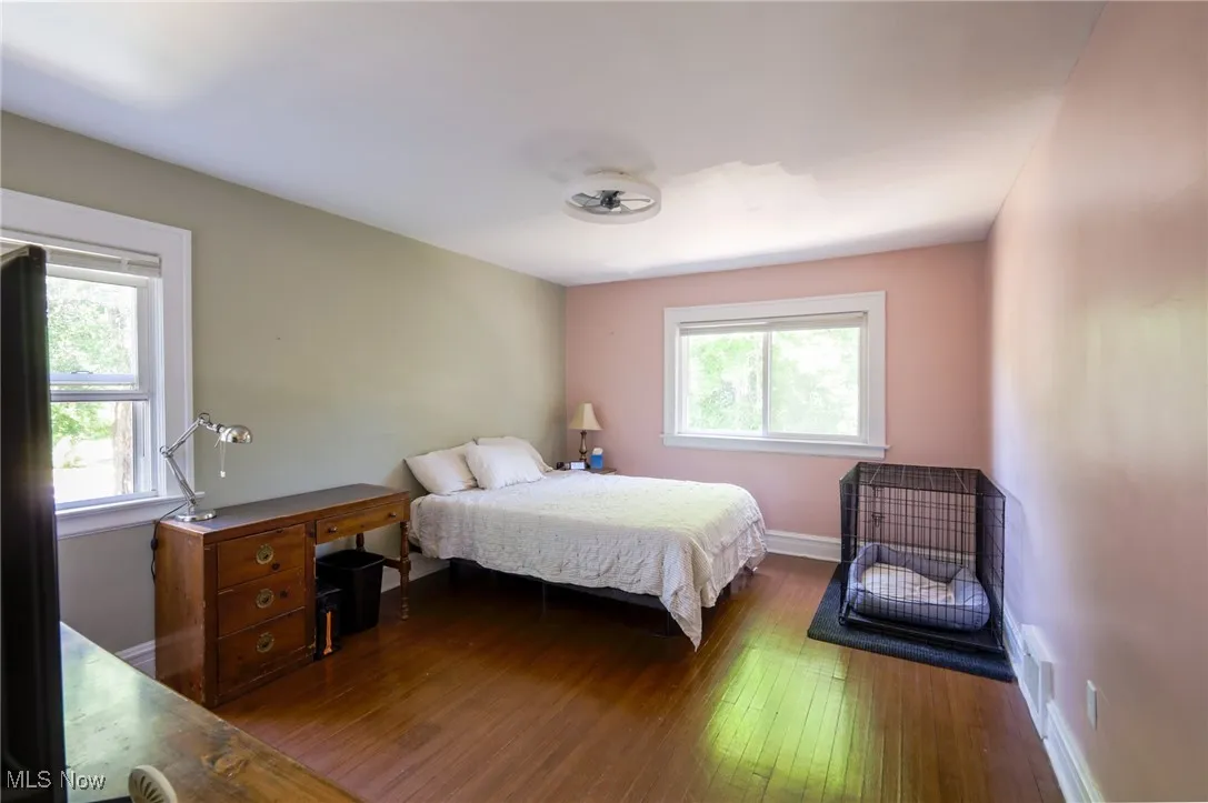Bedroom featuring multiple windows and dark wood-style floors