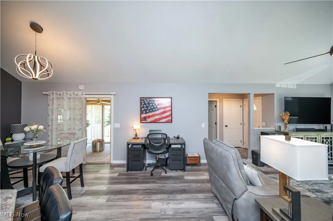 Home office with a chandelier, wood finished floors, and vaulted ceiling