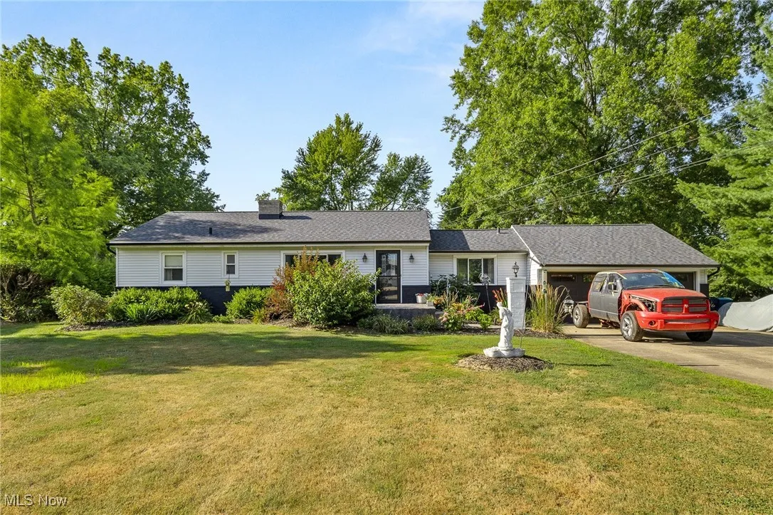Ranch-style house featuring an attached garage, concrete driveway, a front lawn, and a chimney