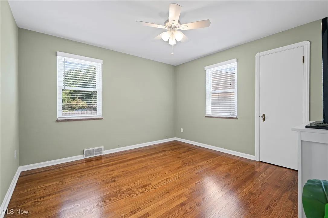 Empty room with wood finished floors and a ceiling fan