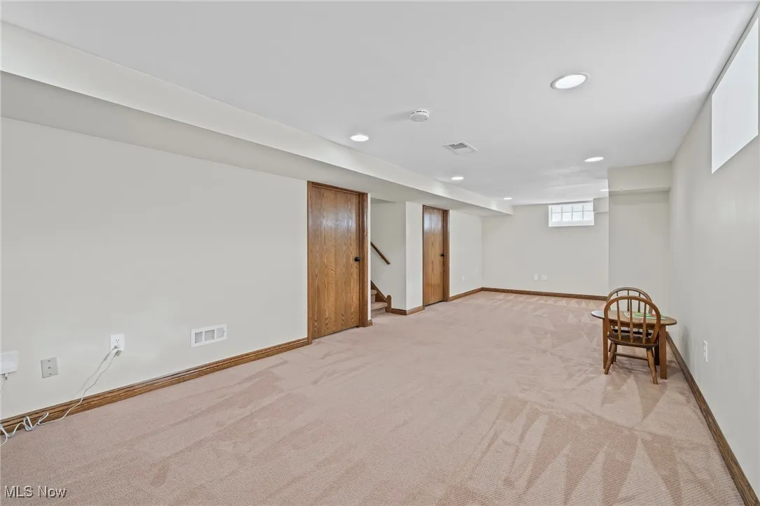 Basement featuring light carpet, recessed lighting, and stairway