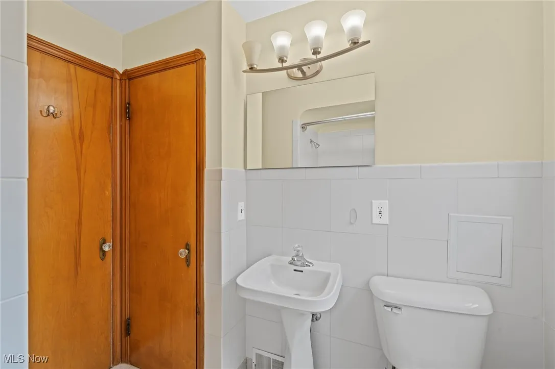 Bathroom with toilet and tile walls