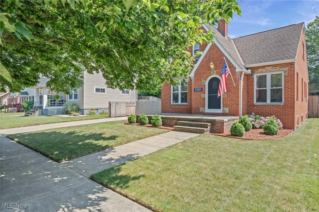 View of front of property featuring brick siding, a chimney, and a shingled roof