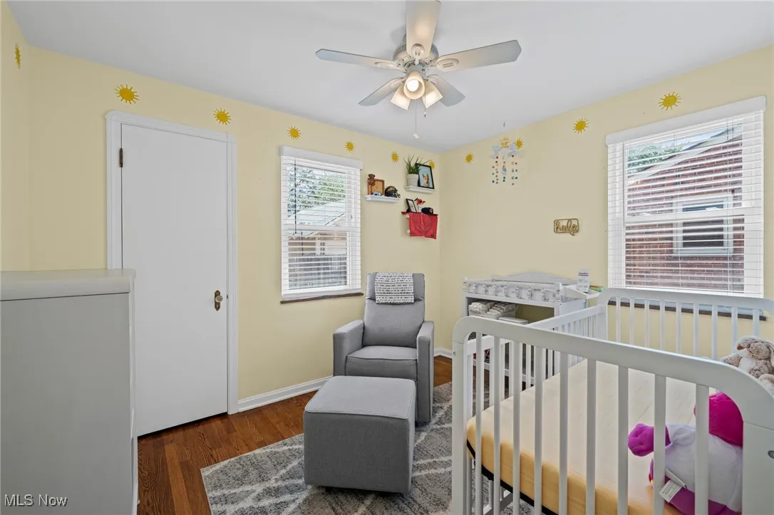 Bedroom featuring wood finished floors, a crib, and ceiling fan