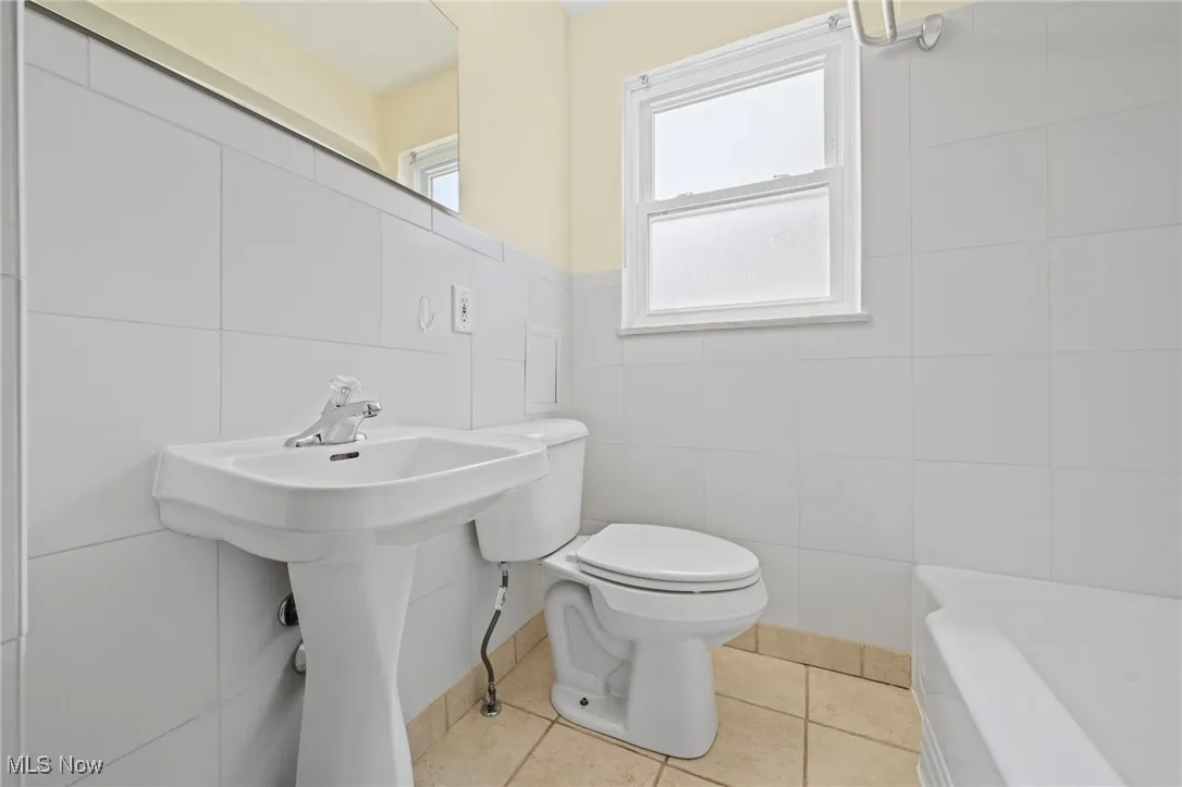 Bathroom featuring tile walls, tile patterned flooring, and a bathtub