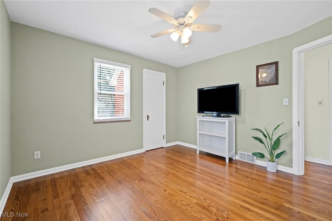 Unfurnished living room with wood finished floors and a ceiling fan