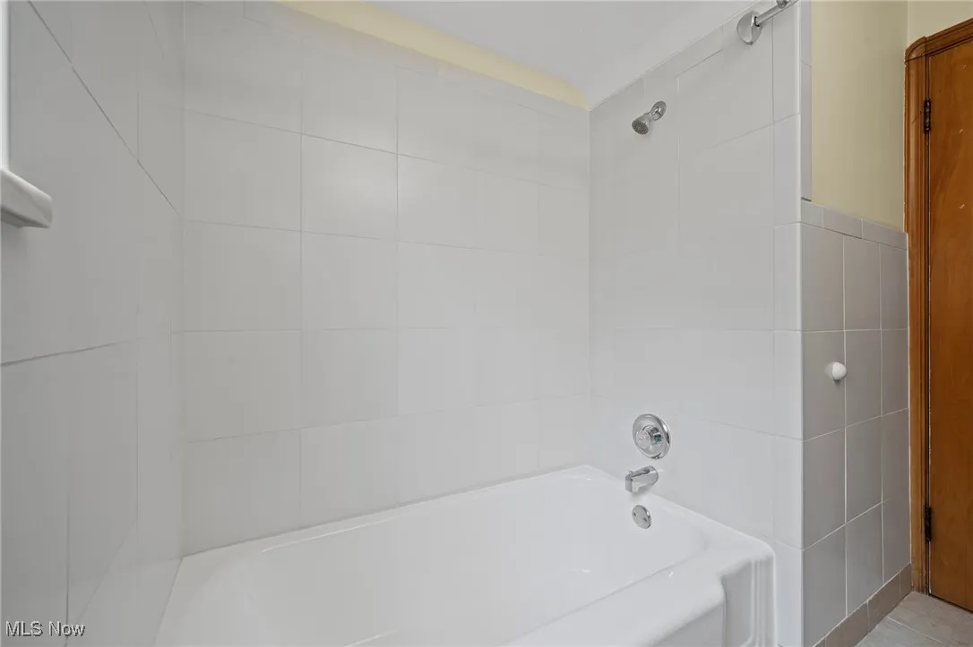 Full bathroom with washtub / shower combination and tile walls