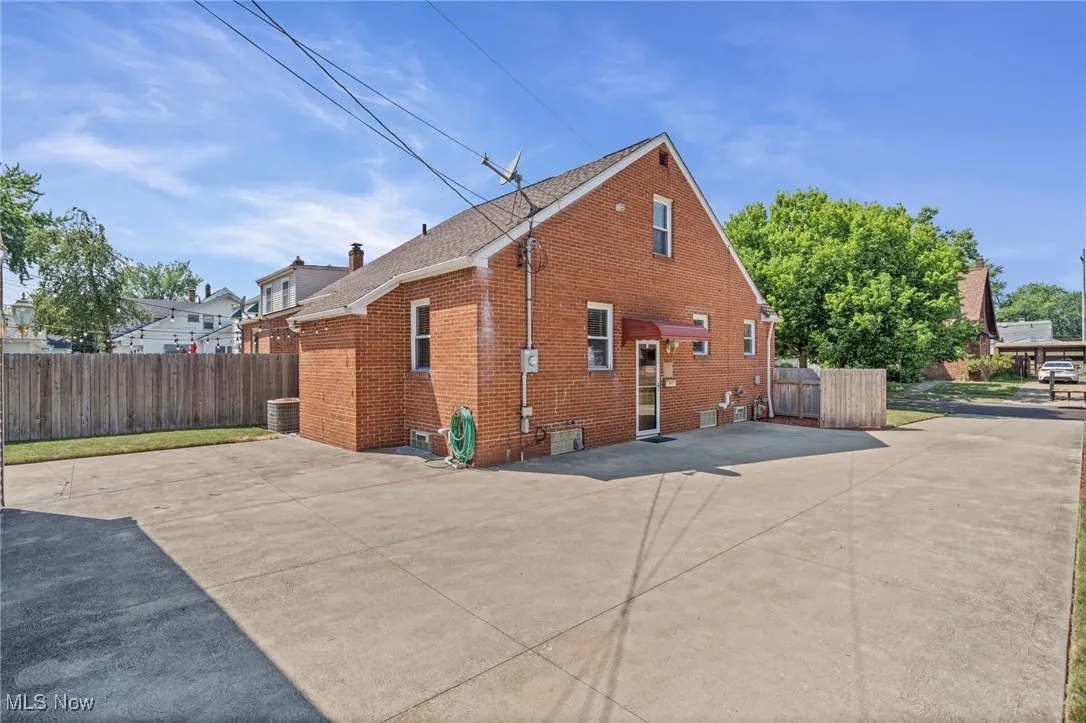 Back of property featuring brick siding, a shingled roof, and a patio