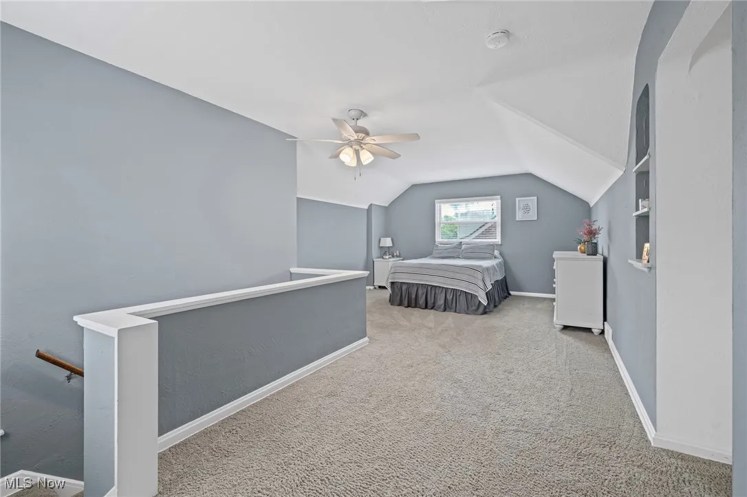 Carpeted bedroom with vaulted ceiling and a ceiling fan