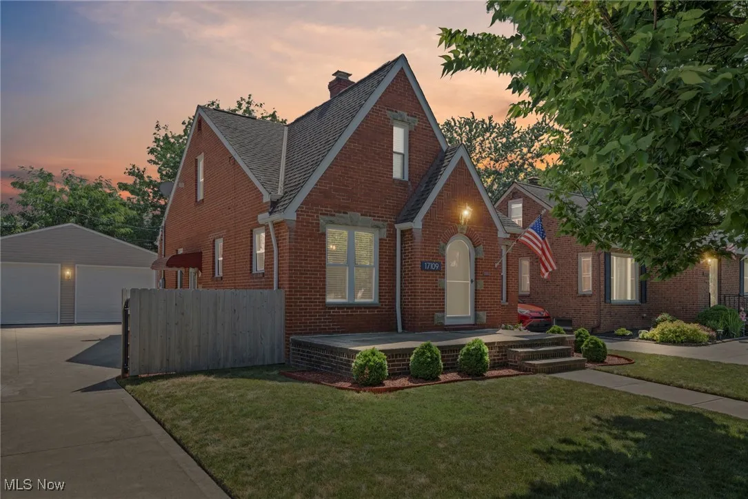 Tudor-style house featuring brick siding, an outbuilding, a detached garage, and a chimney