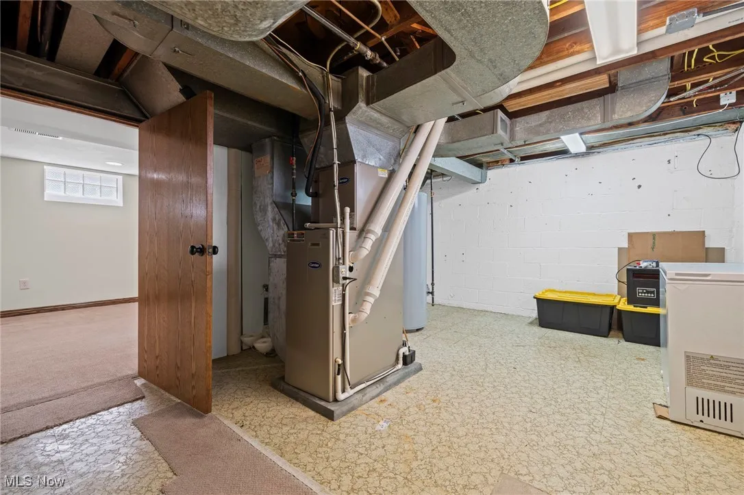Below grade area with tile patterned floors, heating unit, refrigerator, and water heater