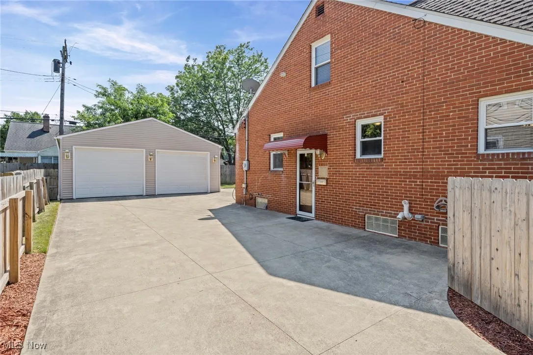 View of property exterior featuring a garage, an outbuilding, and brick siding