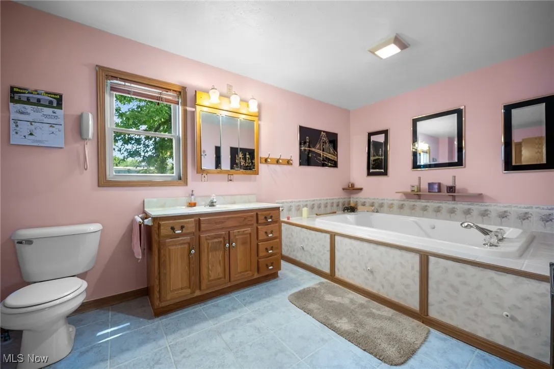 Full bath with vanity, a bath, and tile patterned floors