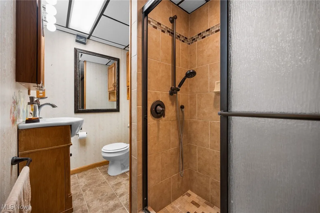 Full bath with a stall shower, vanity, and wallpapered walls
