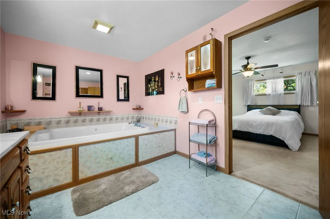 Ensuite bathroom with a garden tub, a ceiling fan, tile patterned flooring, and vanity