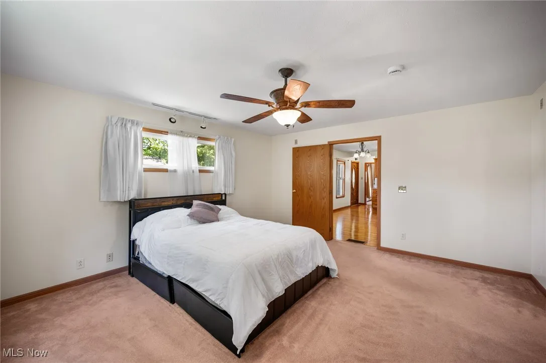 Bedroom featuring light colored carpet, ceiling fan, and a chandelier