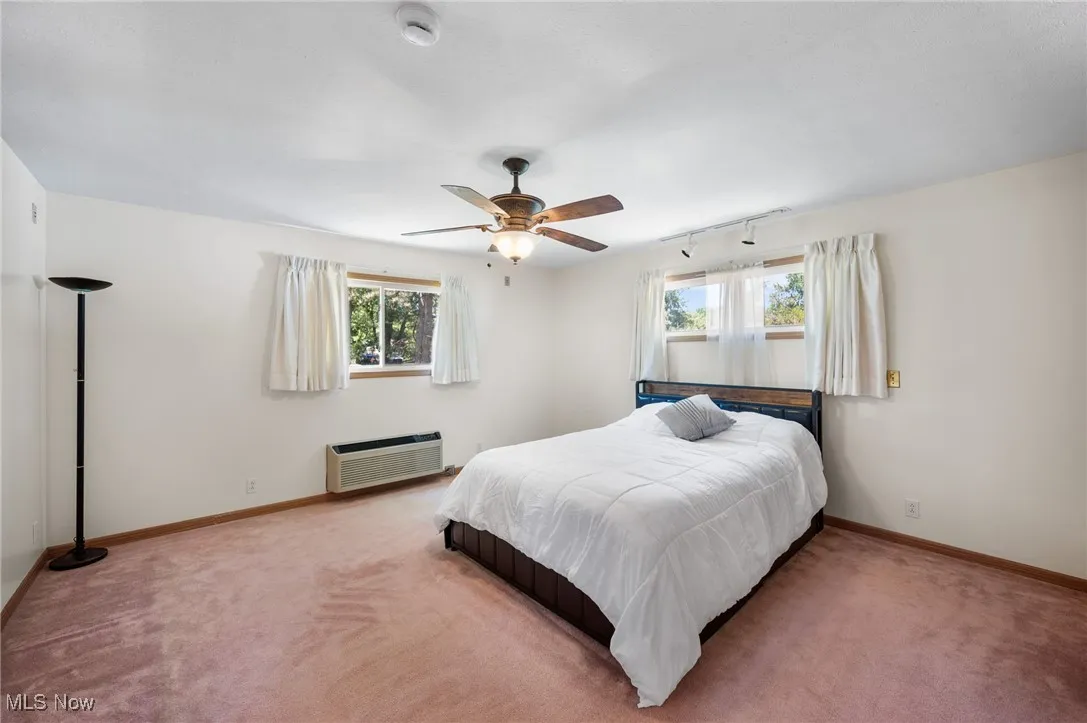 Bedroom featuring carpet, ceiling fan, and a wall mounted air conditioner