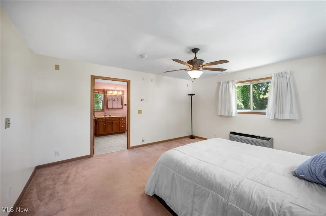 Bedroom with light carpet, a ceiling fan, and ensuite bath