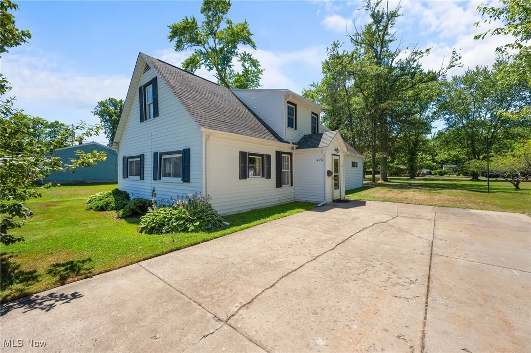 View of front of property featuring a shingled roof, a front lawn, concrete driveway, and a garage