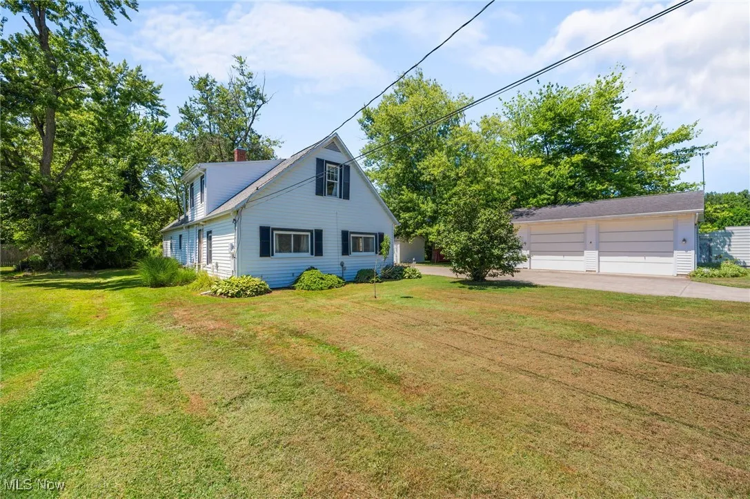 View of front facade featuring a detached garage, a front lawn, and a chimney