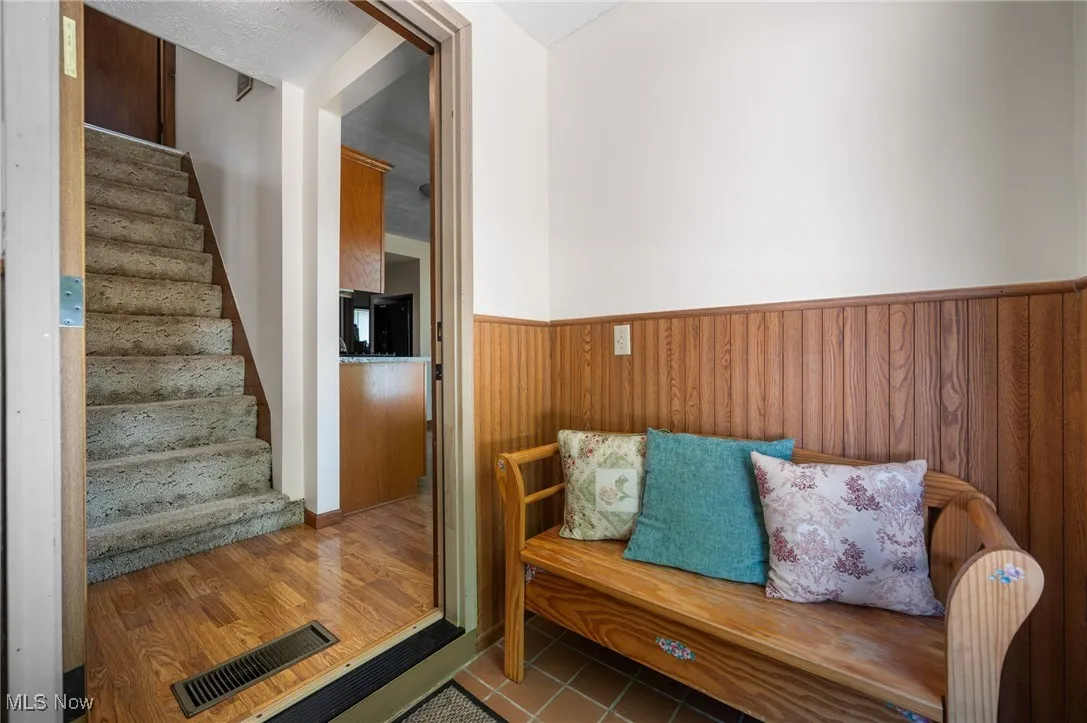Stairway with wood walls, a wainscoted wall, and tile patterned flooring