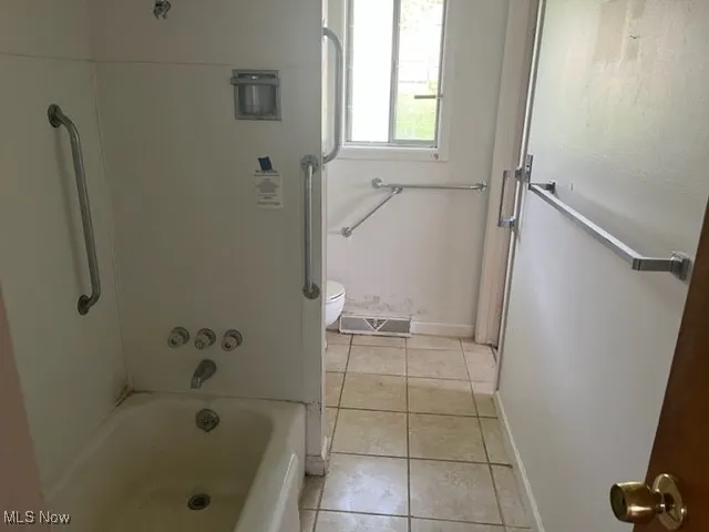 Bathroom featuring tile patterned flooring and washtub / shower combination