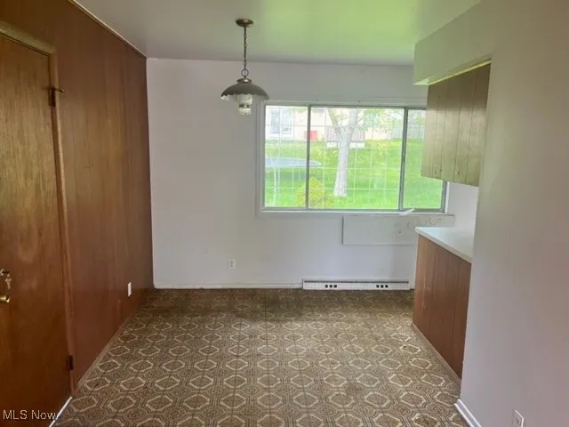 Unfurnished dining area with carpet floors and baseboard heating