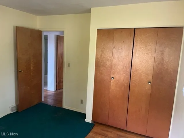 Unfurnished bedroom with wood finished floors and a closet