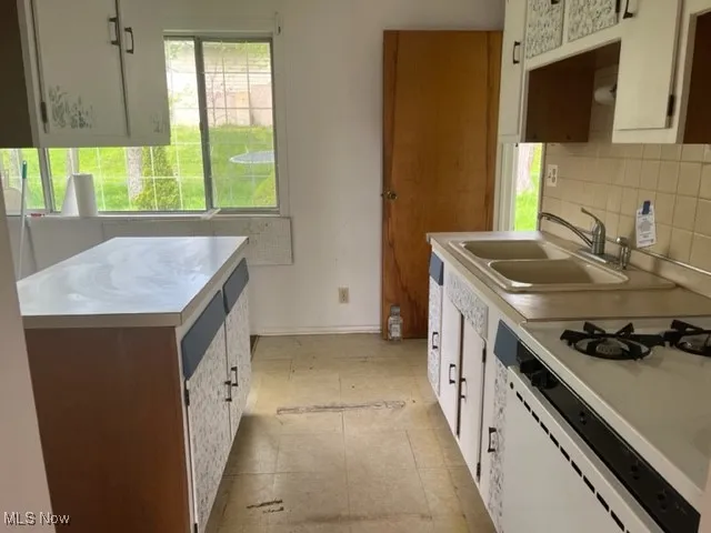 Kitchen with decorative backsplash, light countertops, and stovetop