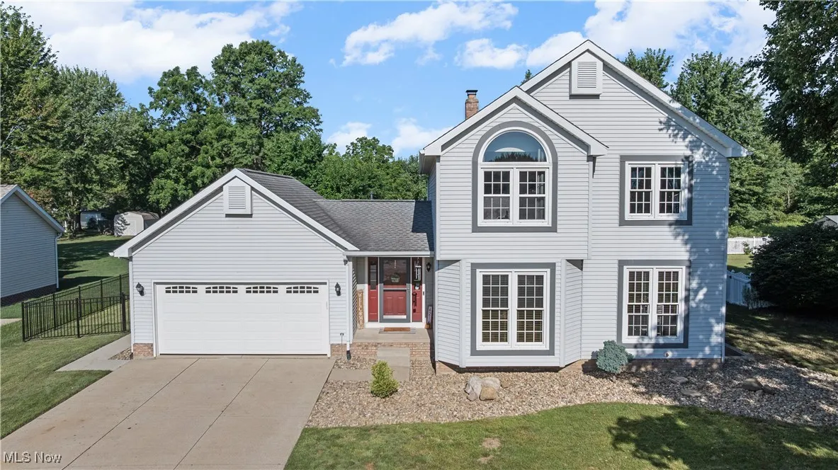 Traditional-style home featuring a chimney, concrete driveway, an attached garage, and roof with shingles