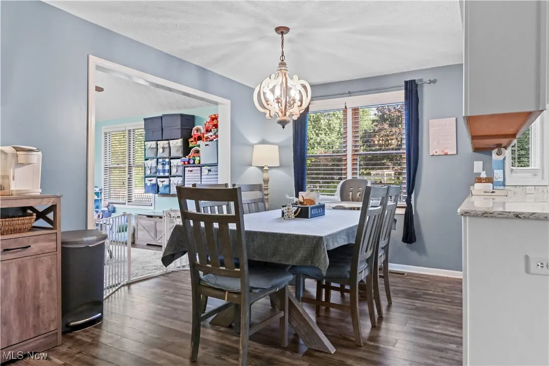 Dining room with a chandelier, dark wood finished floors, plenty of natural light, and a textured ceiling