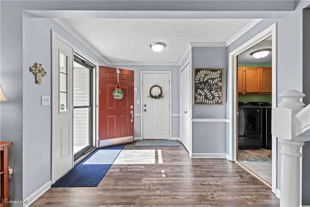 Foyer featuring washer and clothes dryer, crown molding, a textured ceiling, and wood finished floors