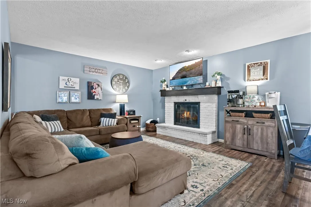 Living area with dark wood-type flooring, a fireplace, a textured ceiling, and recessed lighting