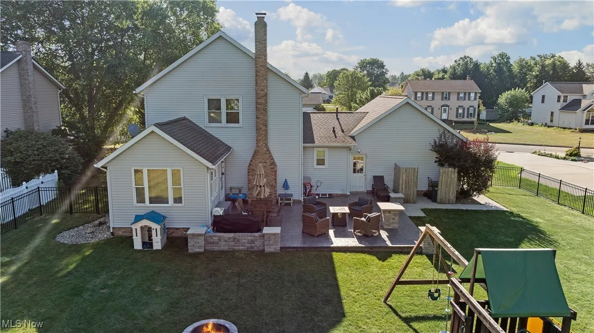 Rear view of property with a patio, a chimney, a fenced backyard, a residential view, and a shingled roof