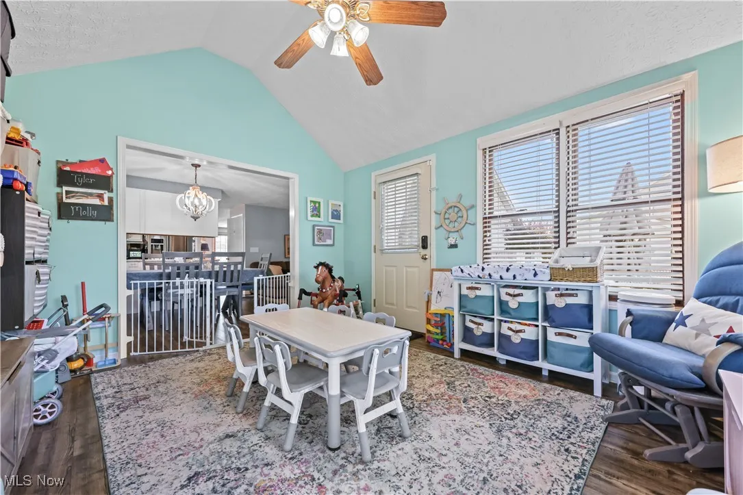 Dining space with ceiling fan, vaulted ceiling, wood finished floors, a textured ceiling, and a chandelier