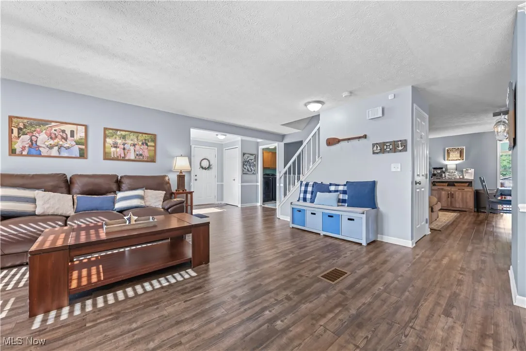 Living room featuring stairs, wood finished floors, and a textured ceiling