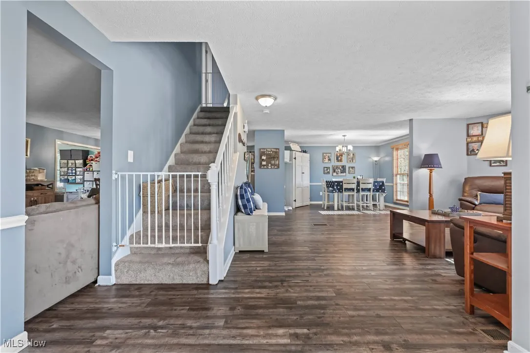 Entrance foyer featuring a textured ceiling, stairs, wood finished floors, and a chandelier