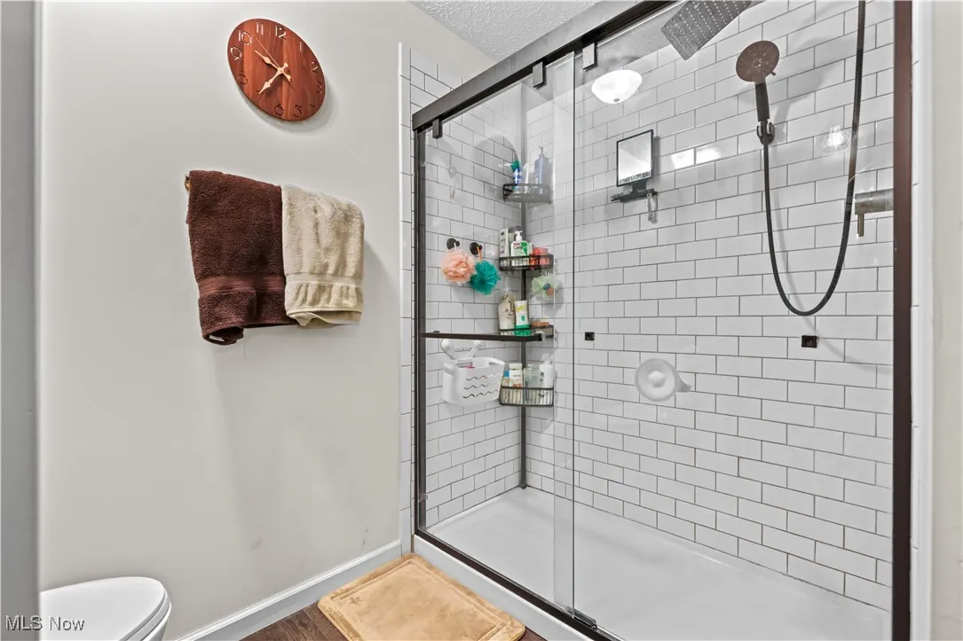 Full bathroom featuring a shower stall, a textured ceiling, and wood finished floors