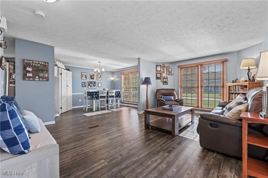Living room featuring a chandelier, wood finished floors, a textured ceiling, and a barn door