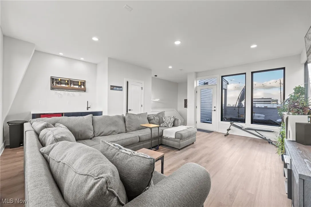Living room with recessed lighting, light wood-style floors, and bar with sink
