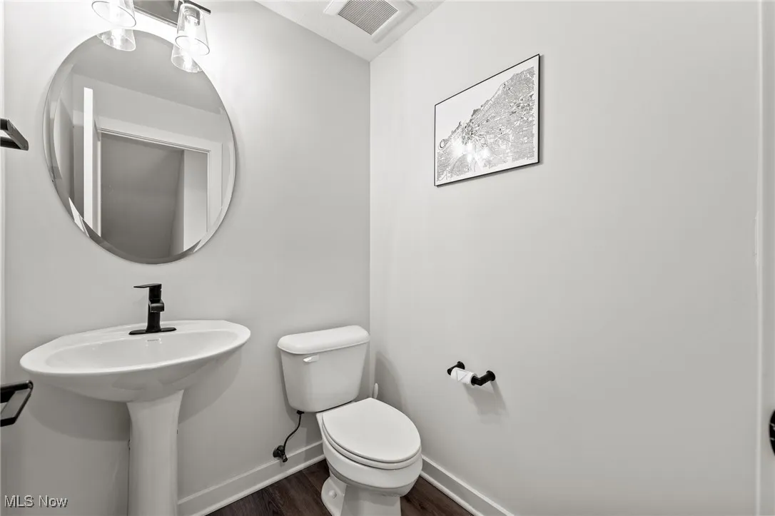 Half bath featuring baseboards and wood finished floors