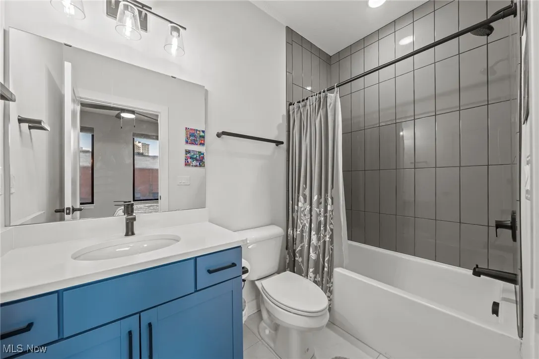 Bathroom featuring vanity, shower / tub combo with curtain, and tile patterned floors