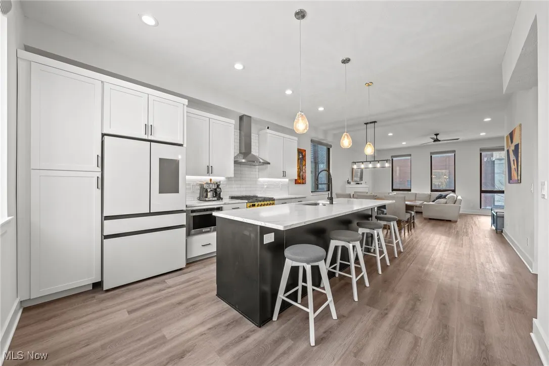 Kitchen with white refrigerator, recessed lighting, open floor plan, an island with sink, and white cabinets