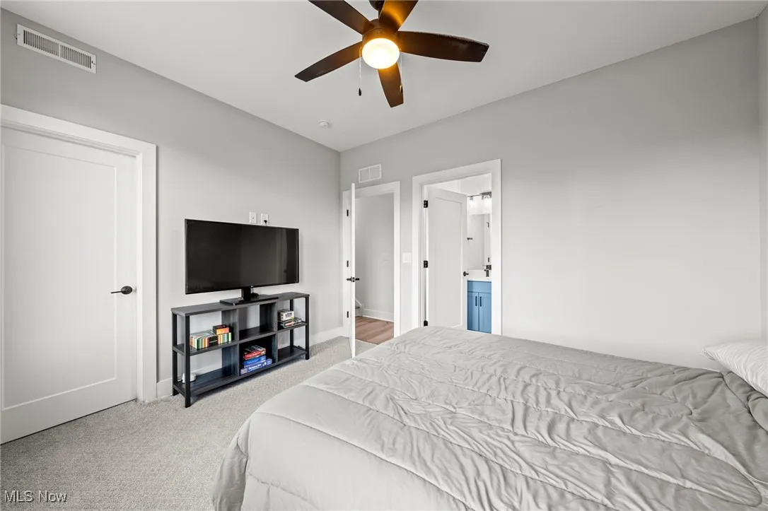Bedroom featuring carpet flooring, a ceiling fan, and ensuite bath