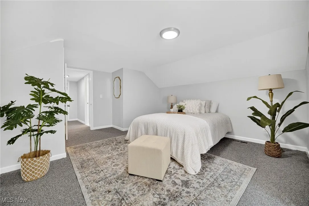 Carpeted bedroom featuring baseboards and vaulted ceiling