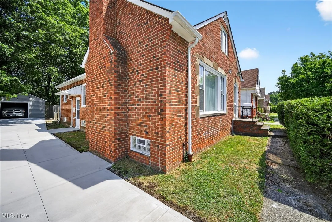 View of side of home featuring brick siding, an outdoor structure, a chimney, and a detached garage